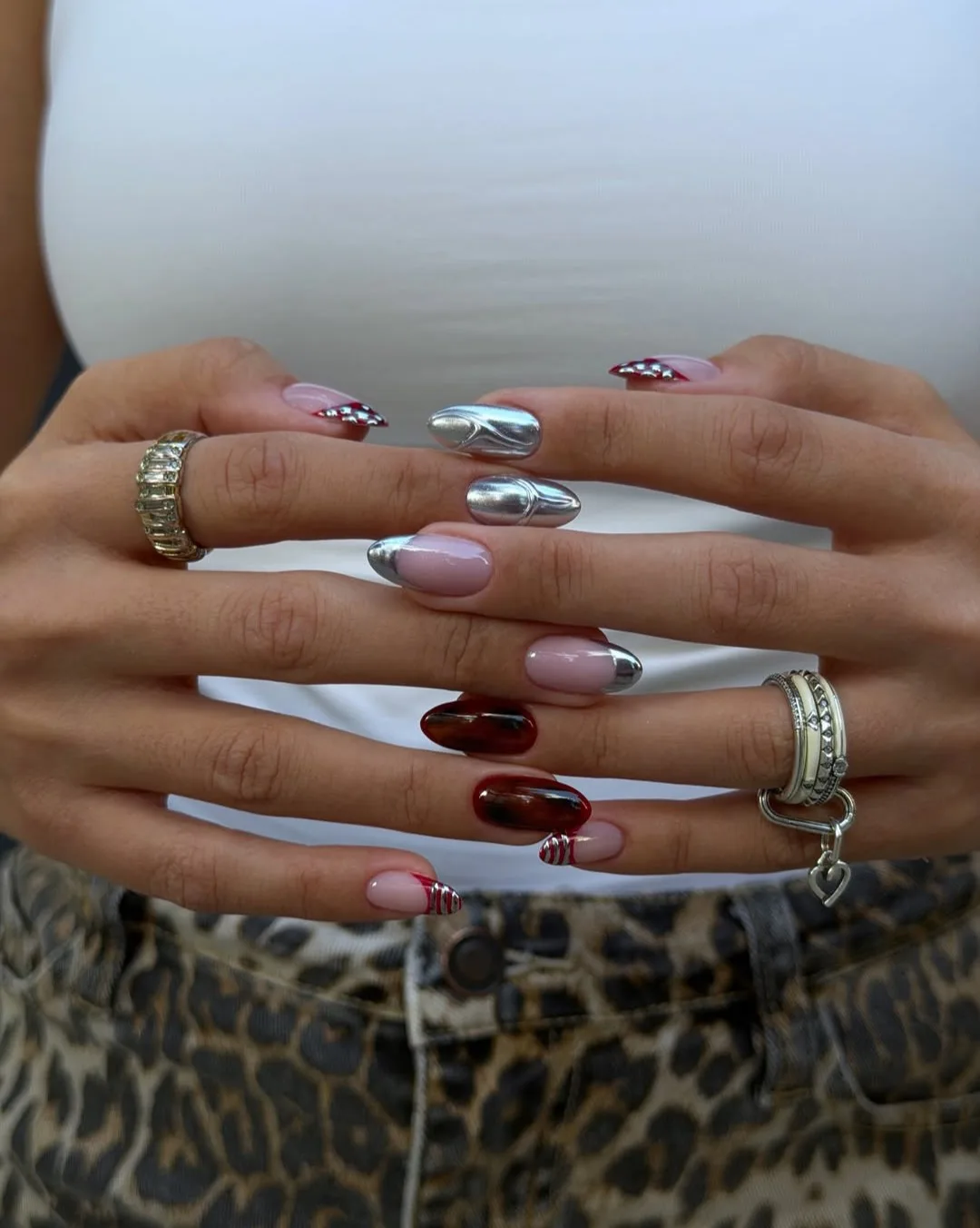 Almond November nails mixing silver chrome, burgundy tortoiseshell, and red French tips with silver stripes