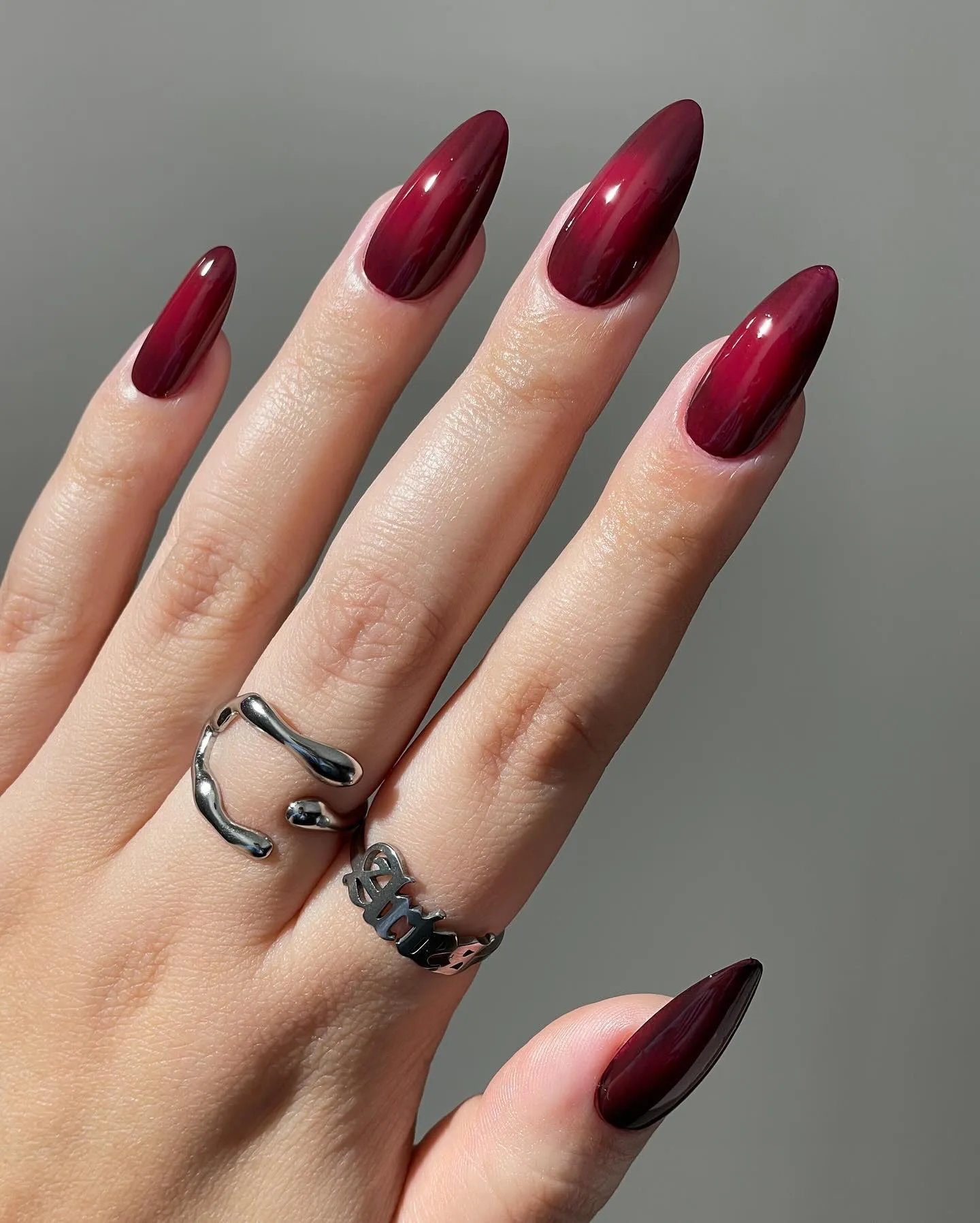 Long almond fall nails in glossy cranberry red jelly with a soft darker edge