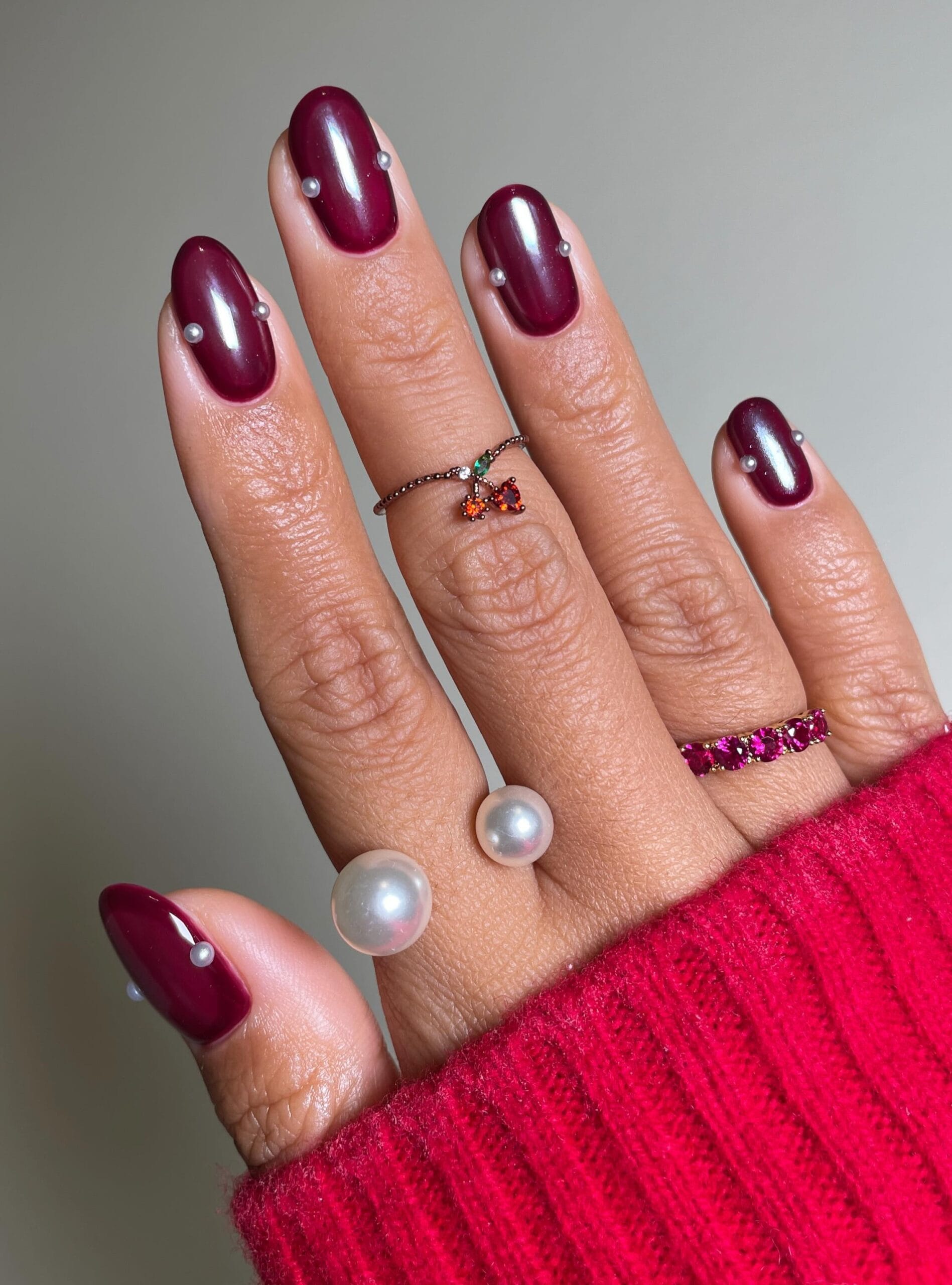 Short oval autumn nails in deep cranberry with tiny pearls set along the sides
