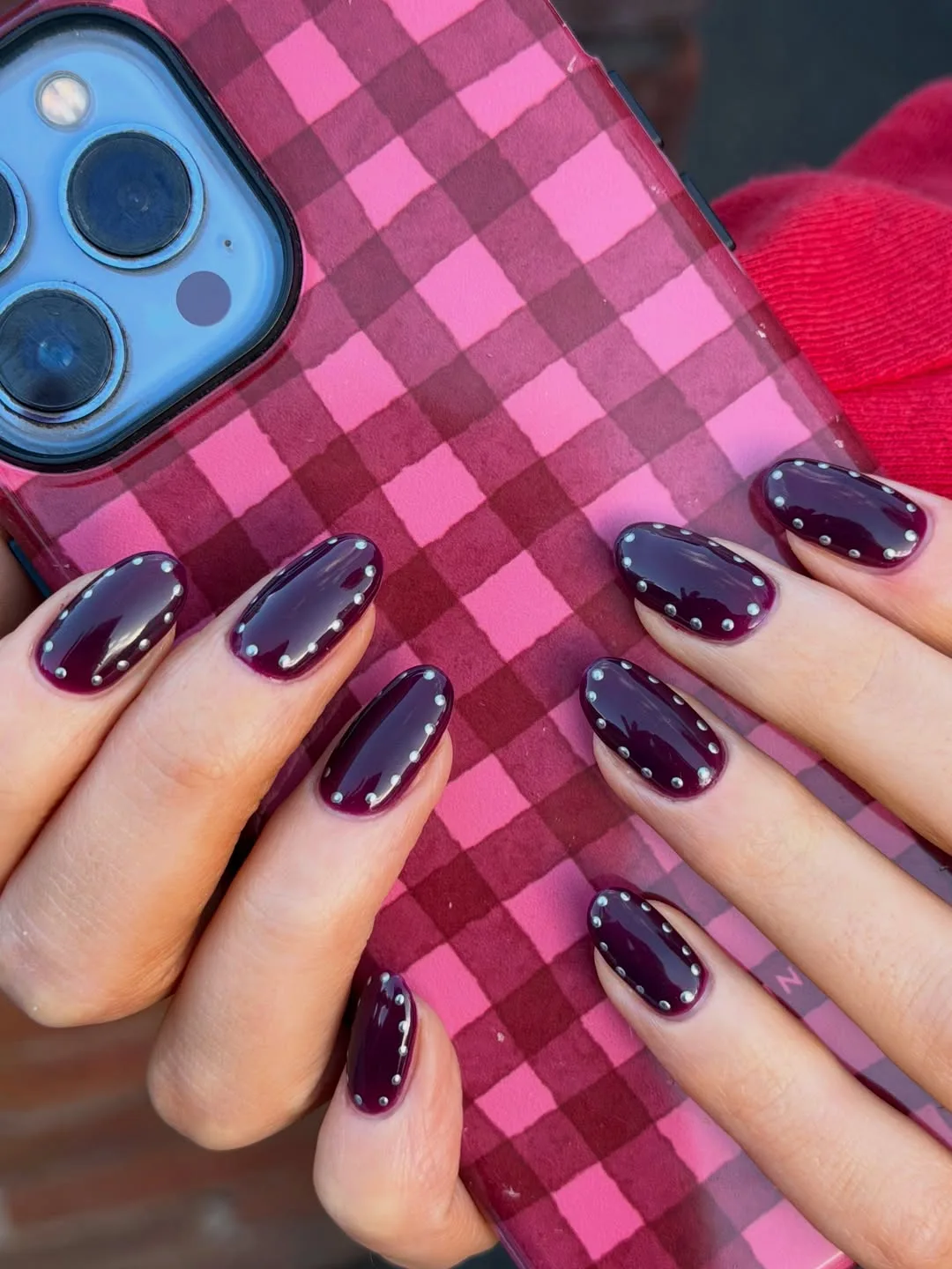 Oval November nail colors in dark blackberry plum outlined with tiny silver studs