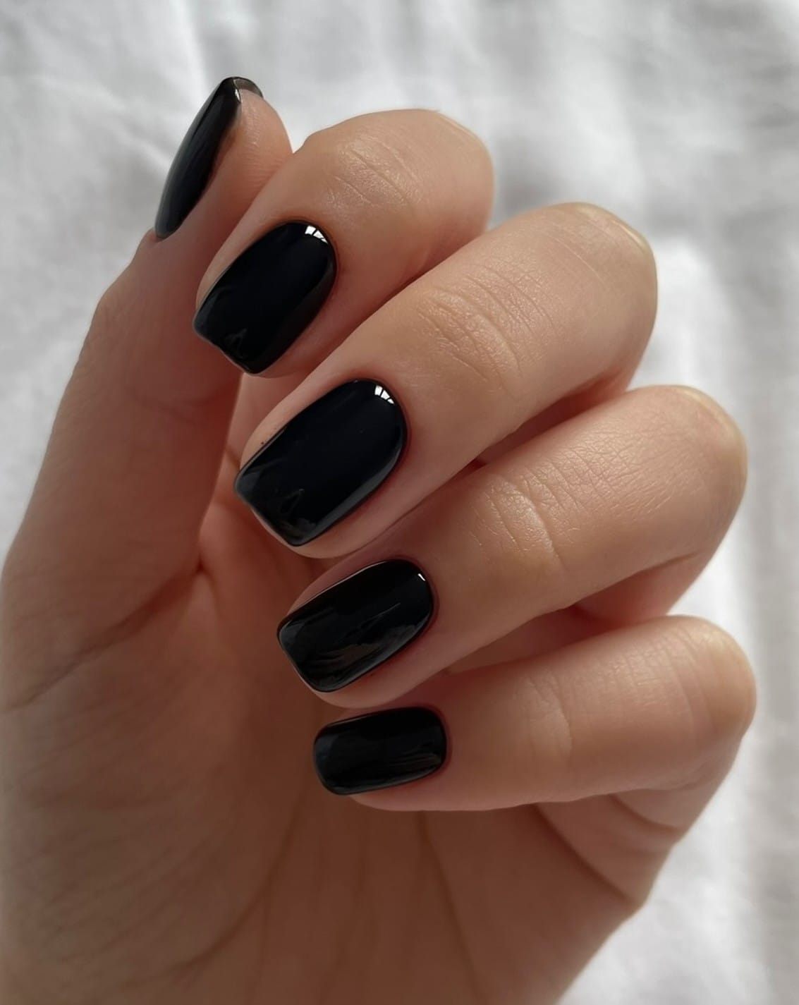 Short square autumn nails in glossy black with a smooth, mirror-like finish
