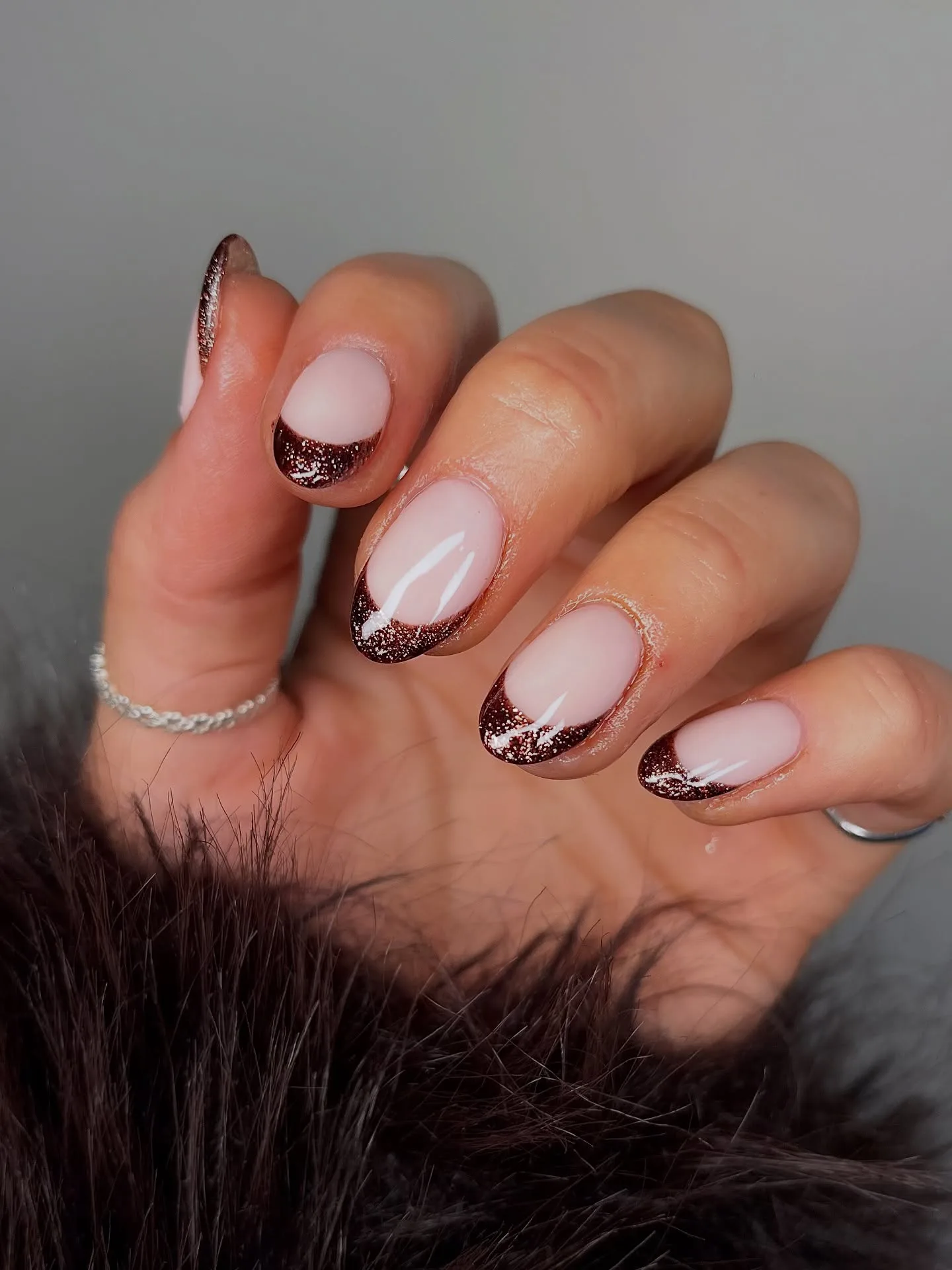 Short oval fall nails with a sheer pink base and shimmery chocolate brown glitter French tips